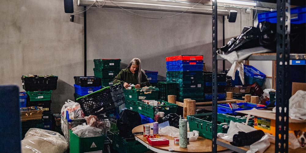 Woman stood working in a room full of boxes and crates