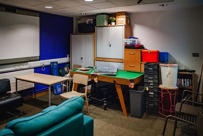 cramped room with a small sofa and games table